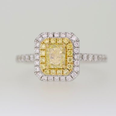 Anillo de compromiso con diamante central amarillo y orla de diamantes amarillos y blancos.