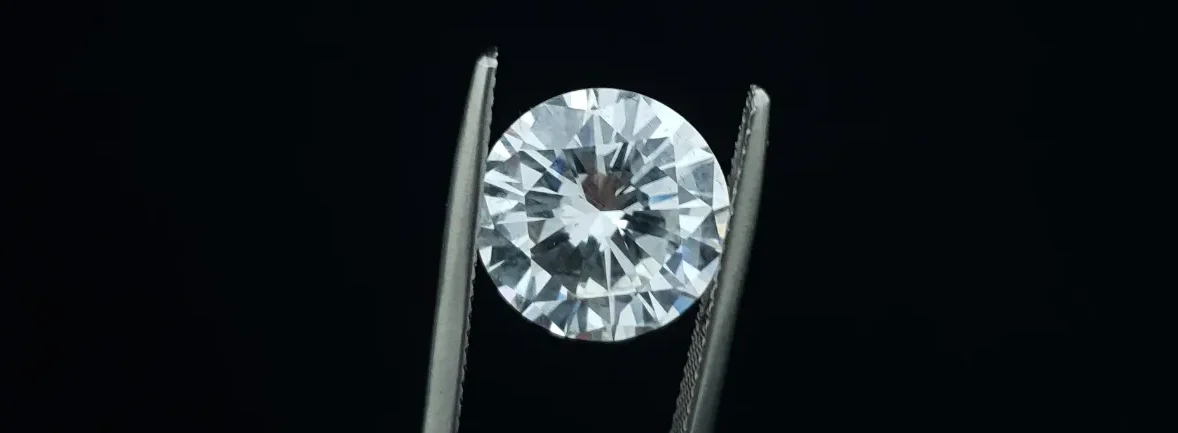 Un diamante brillante en un pinza, sobre un fondo negro.